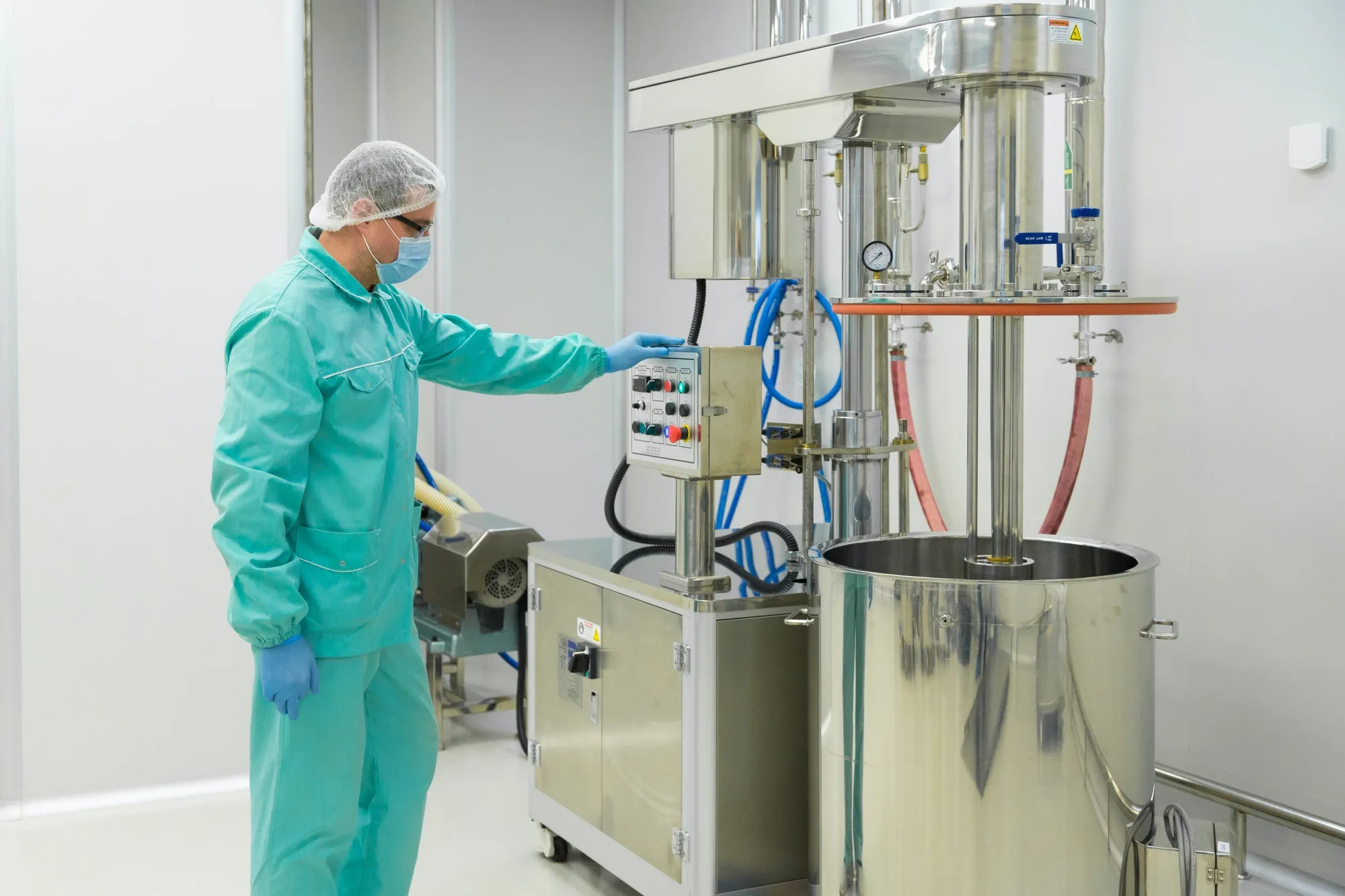 Pharmaceutical factory man worker in protective clothing working with control panel in sterile